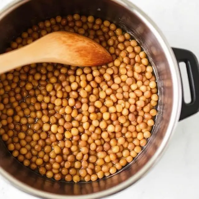 Lentils cooking in a pot with vegetables and spices.